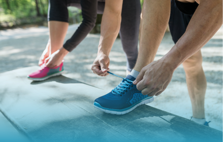 A Couple Tying Their Shoelaces On Exercise Shoes.