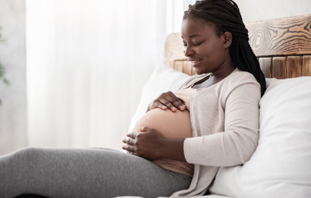 Black Pregnant Woman Relaxing On Bed At Home