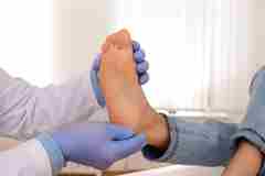 A healthcare professional checking someone's foot. 