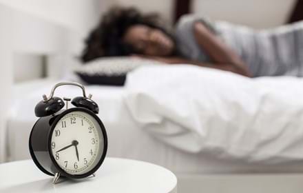 Alarm Clock Near Sleeping Person