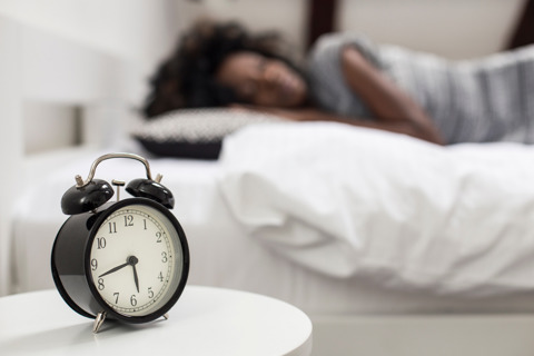 Alarm Clock Near Sleeping Person