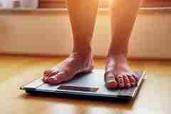 A person weighing themselves on scales. 
