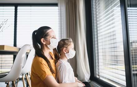 Mother And Child With Face Masks Looking Through Window