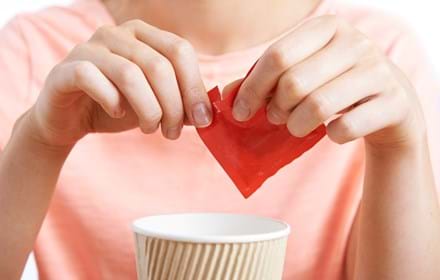 Woman Adding Artificial Sweetener To Drink